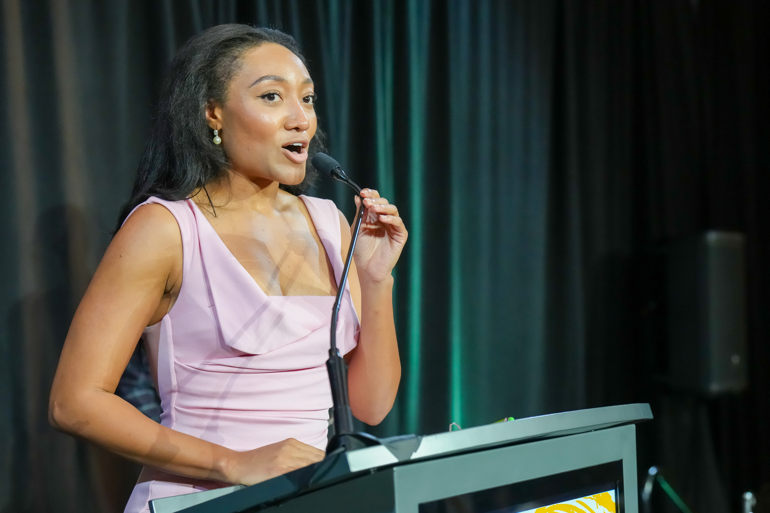Woman speaking at a podium during a nonprofit event photographed by EyesOpen Creative Media Group